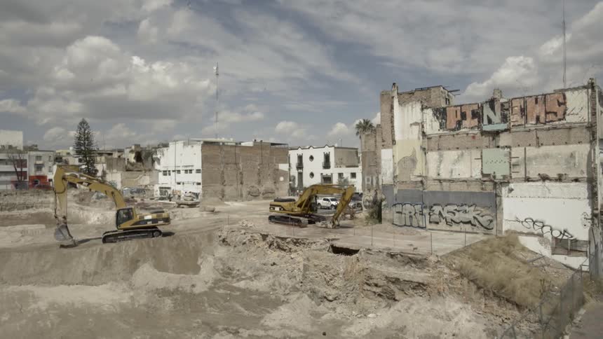 Large construction equipment roll on a dirt site