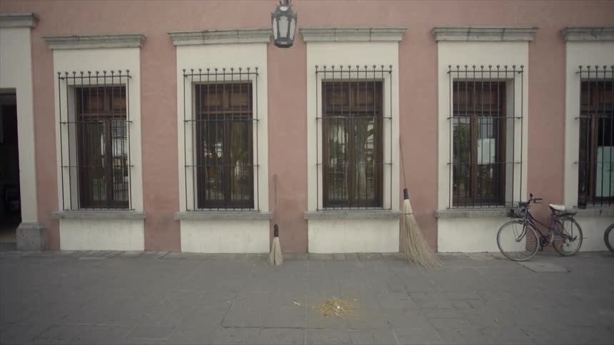Brooms and bicycle sit on an empty sidewalk