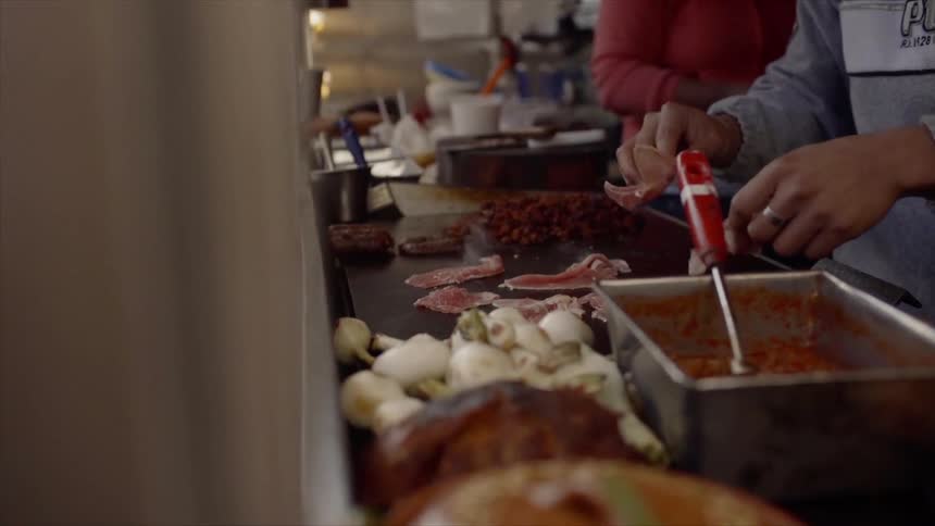 A person is tearing meat apart from a flat indoor grill