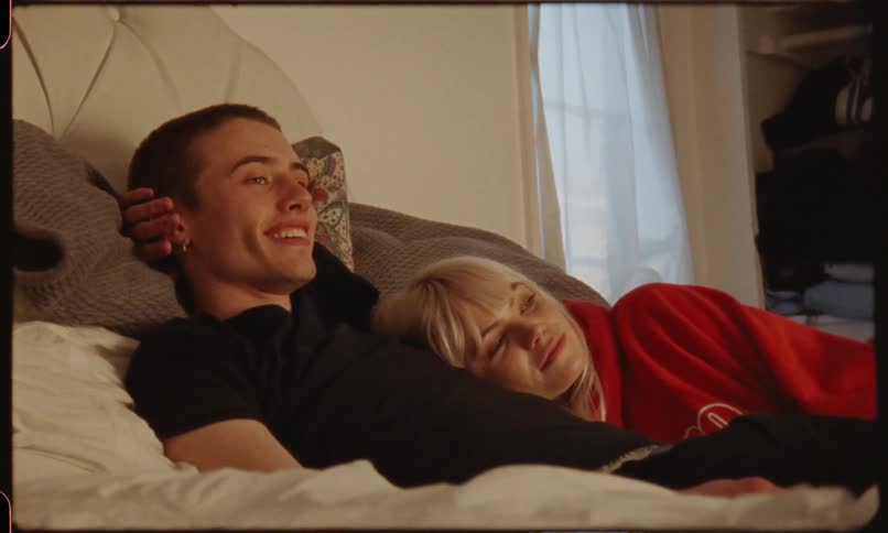 Man and blonde woman lie down on the bed and laugh in bedroom