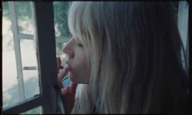 A woman sits on the window sill and smokes a cigarette at daylight