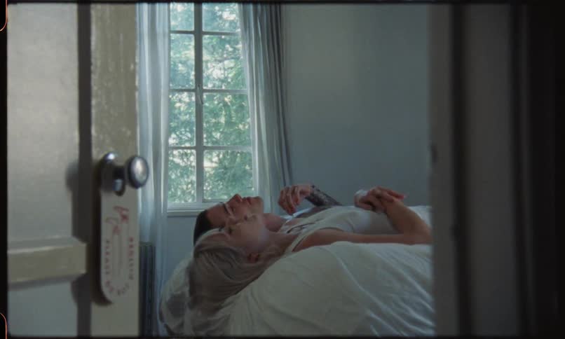 A couple lay supine on a bed in a period house and talk