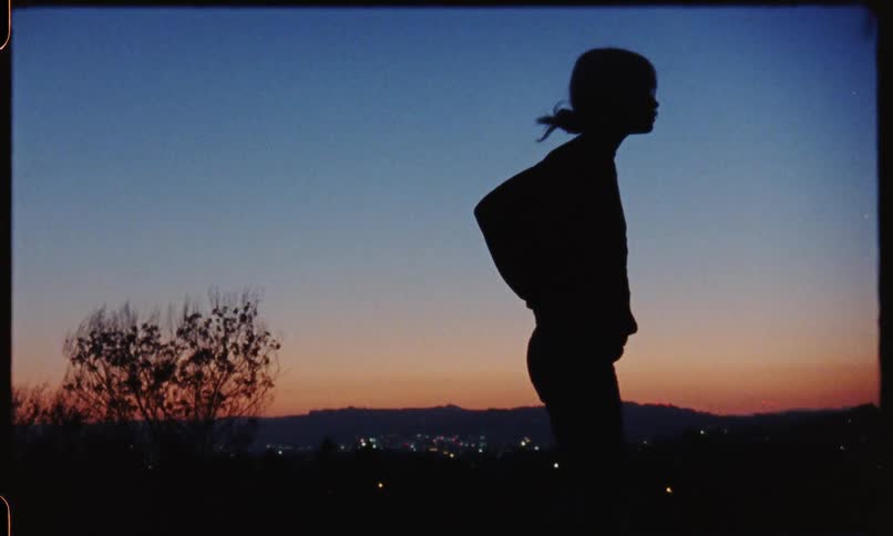 A woman scuffs her shoes into the ground during sunset