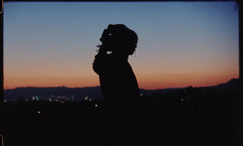 A silhouette of woman warming up on the hill at sunset