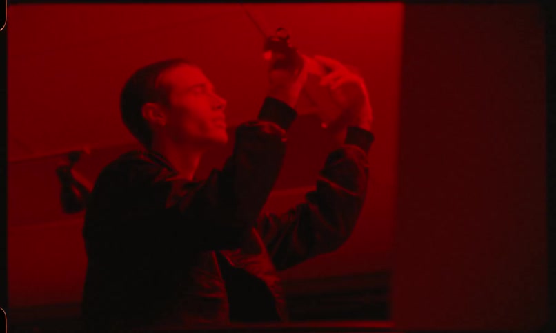A man holds up photo negatives in a dark room