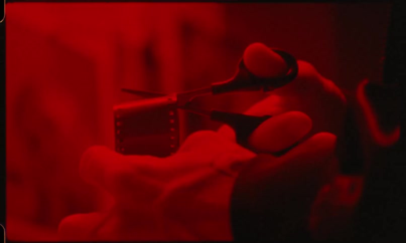 Filmstrip being cut with scissors in a darkroom