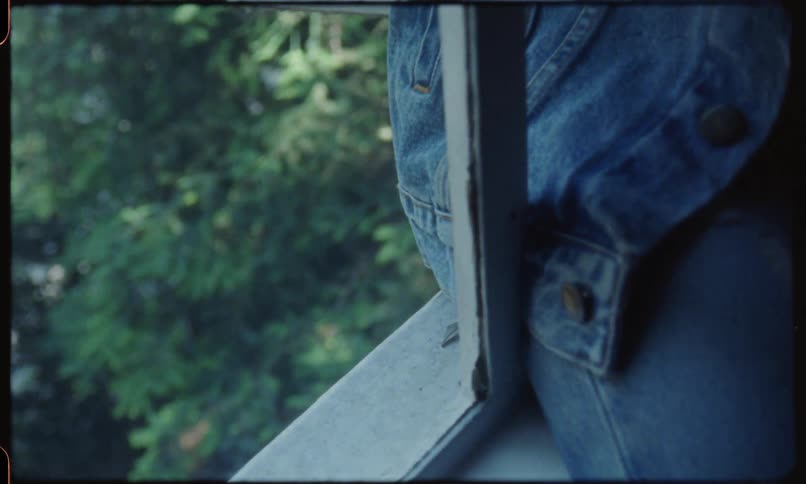 A woman sits on a window ledge and smokes