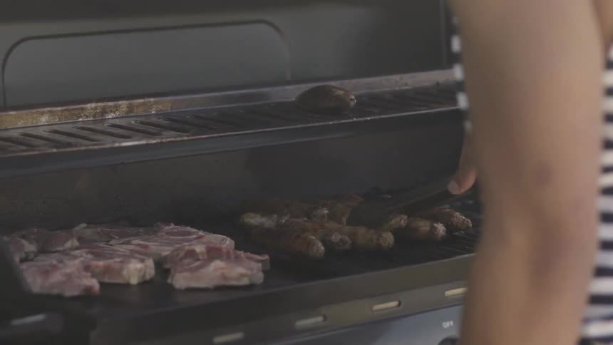 Person Grilling Steaks Outdoors Over Open Flame During Casual Cooking Scene.