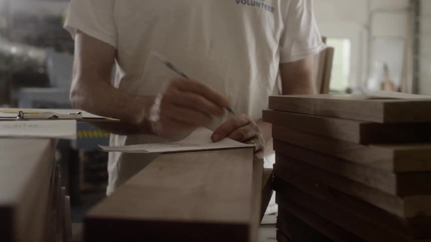 A man writing a note on top of a bunch of wood pieces