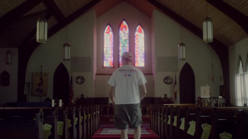 Man with white hat and shirt prays at the church