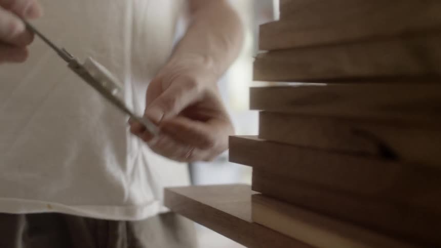 A man uses a tool to measure the width of some wood