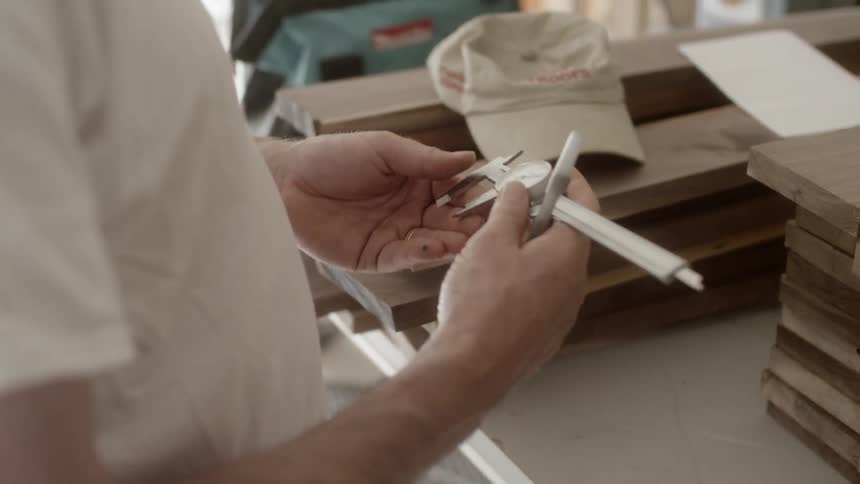 A man uses a tool to measure some wood