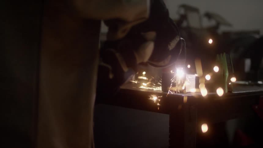 Man welding an object with a tools in the dark