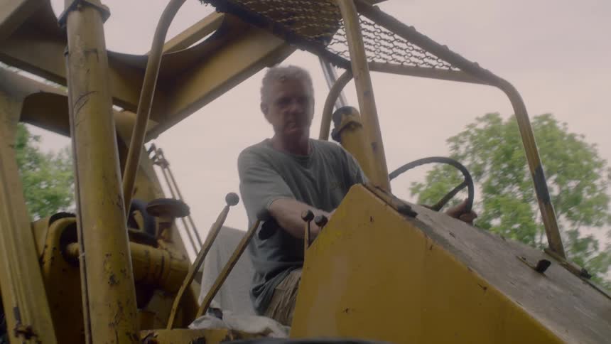 An elderly man operating a heavy machine