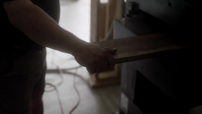 A man placing a piece of wood in a machine