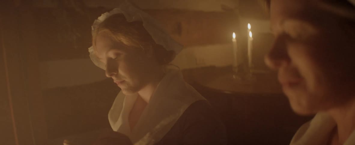 Two women smile at each other in a dark room