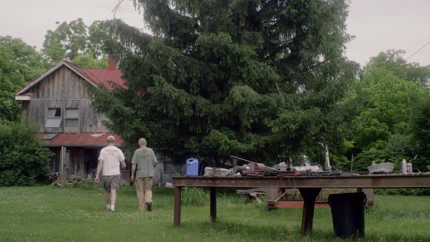 Two men outside walking towards a gray in red house