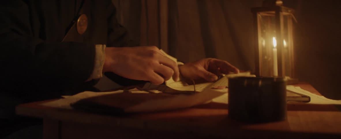 Man writes letter in tent by candlelight