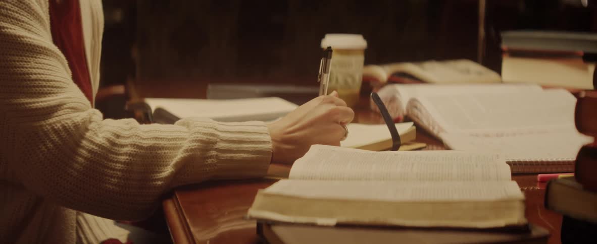 Woman with white sweater writing on a book