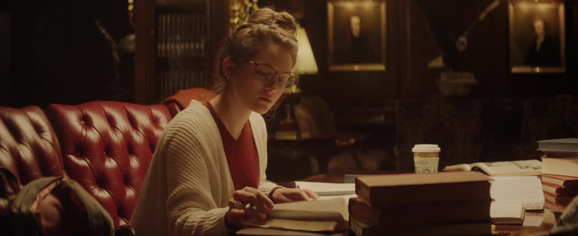 Woman with hair in bun reading in the living room at night