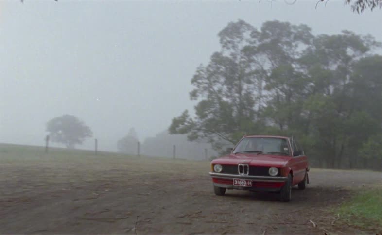 Red car driving on the foggy rural roads