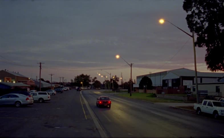 A car drives down a narrow road in a small town