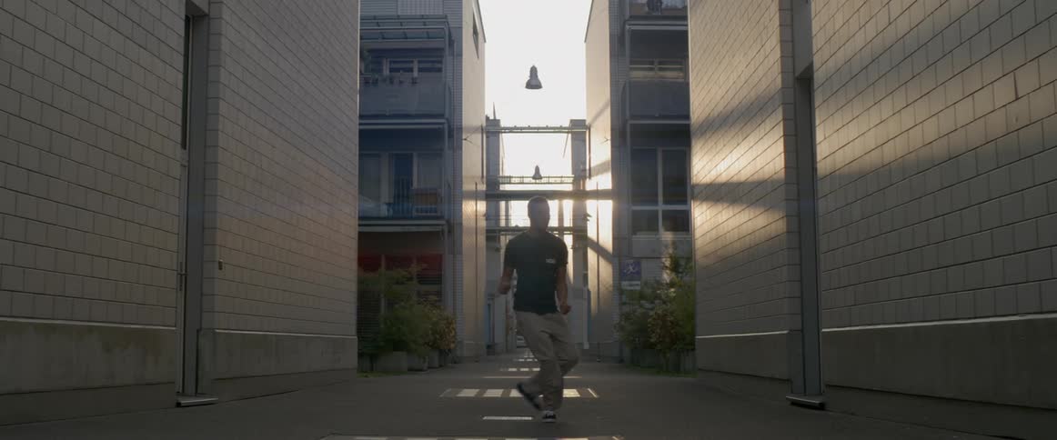 A man dances in the alley between two buildings