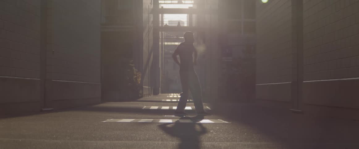 Man dances in the sunlight between the buildings