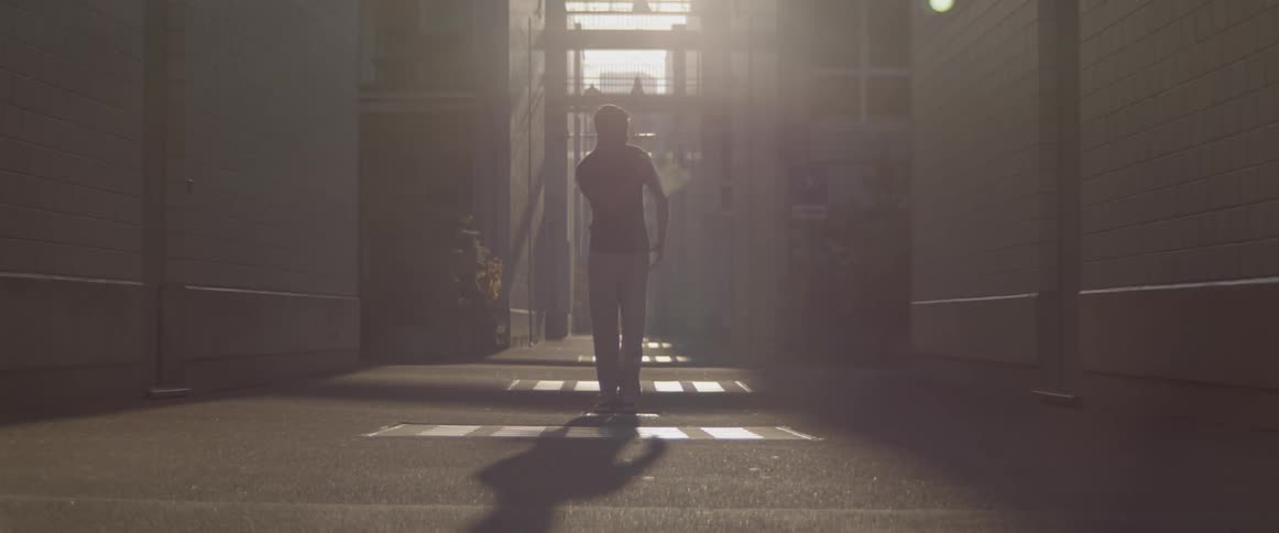 A man dancing in a dim alleyway in cold weather