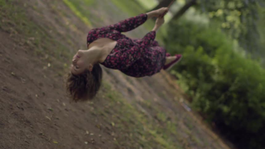 A woman is swinging in a yard on a sunny day