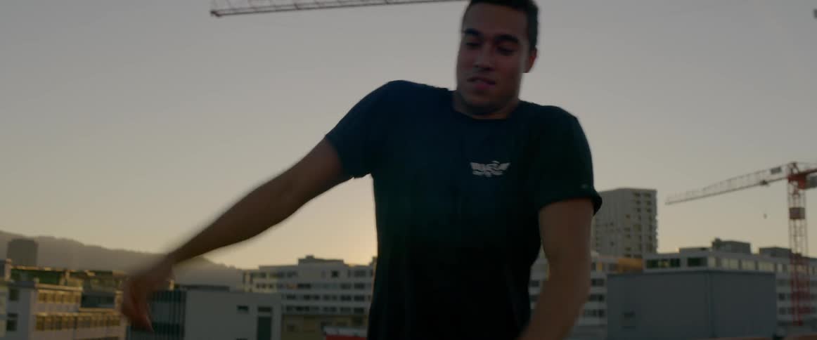 Man dances on the roof of a building at sunset