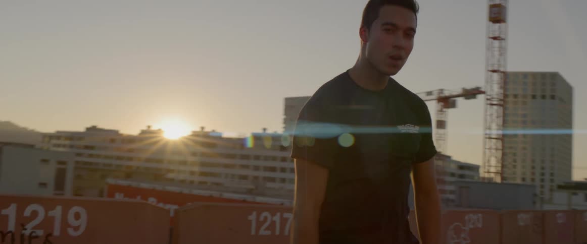 Man dances on the roof of a building at sunset