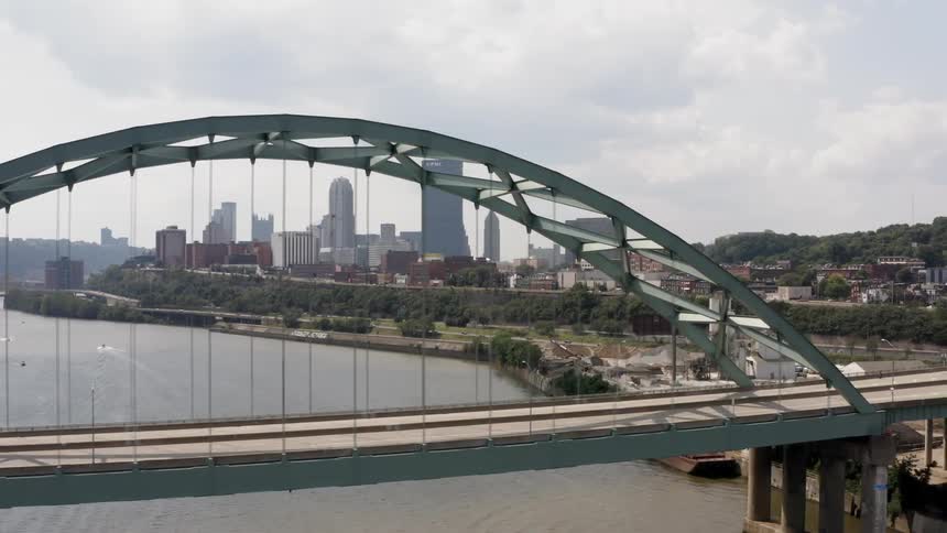 A car travels over the large bridge towards the city