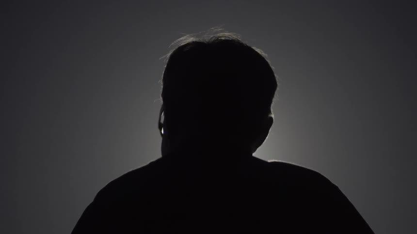 Silhouette of Person Standing Against Vibrant Sunset Sky in Calm Outdoor Setting.