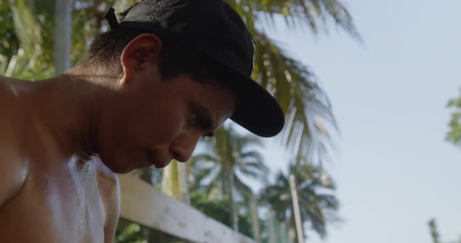 Shirtless sweaty man looks down and breathes during daylight