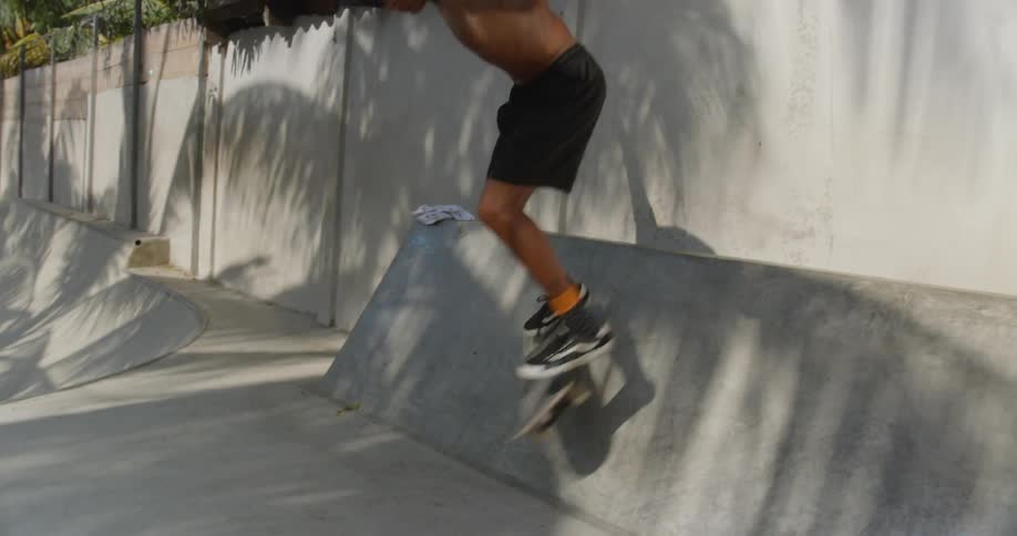 A man in a skate park falling off a skateboard