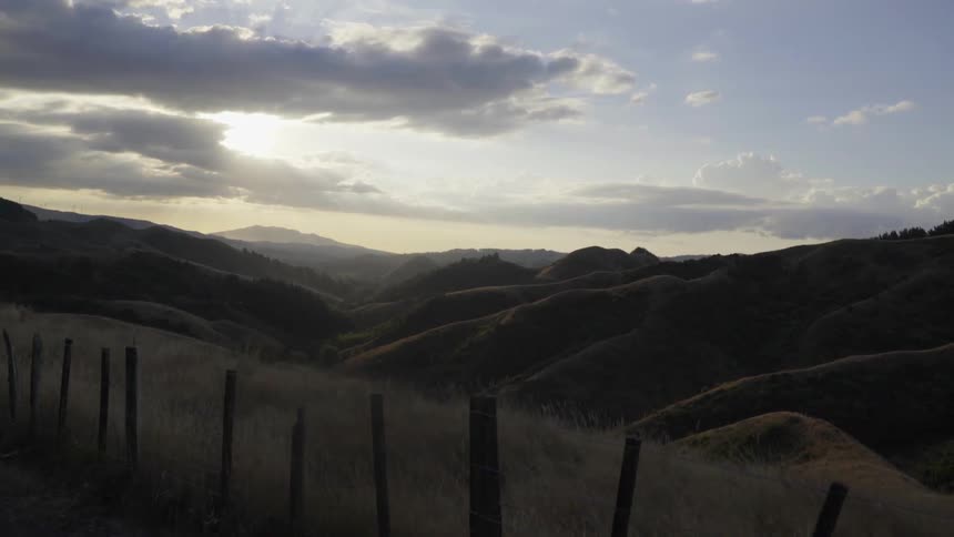 The sun breaking through clouds over some hills