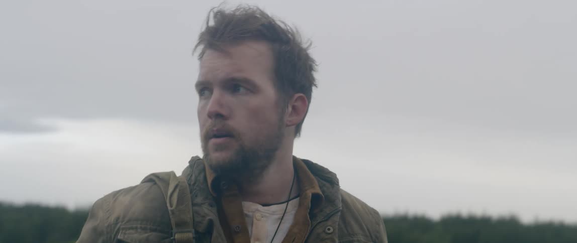 A man stands in a vast open field and looks around