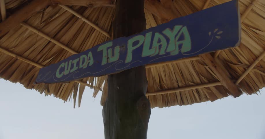 A sign with text hangs on a palapa