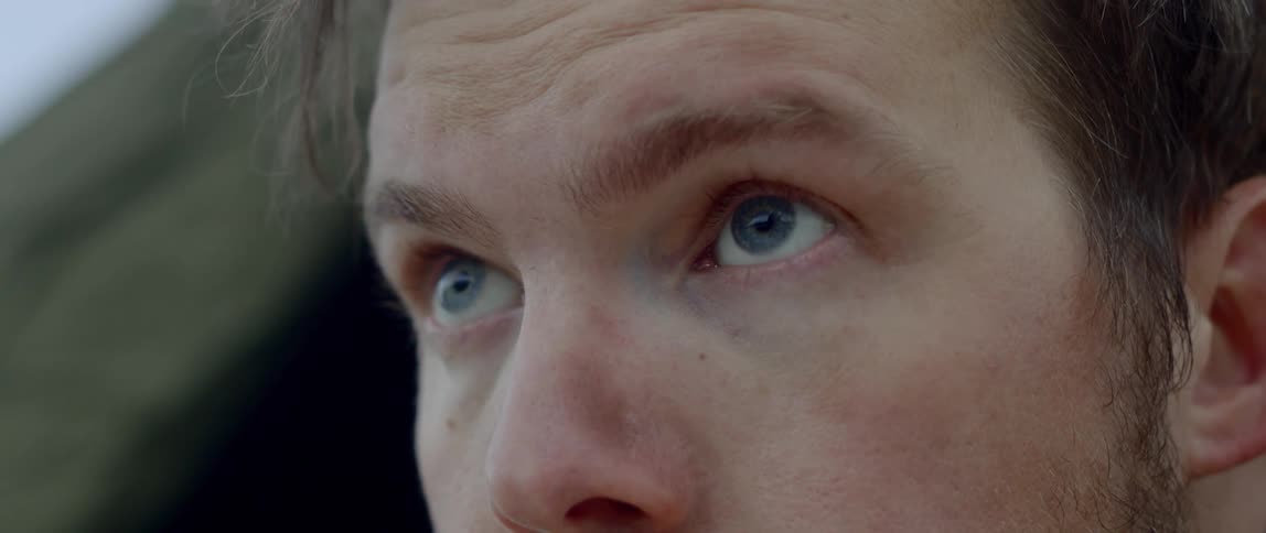 Blue eyed man looks a head and blinks during daylight