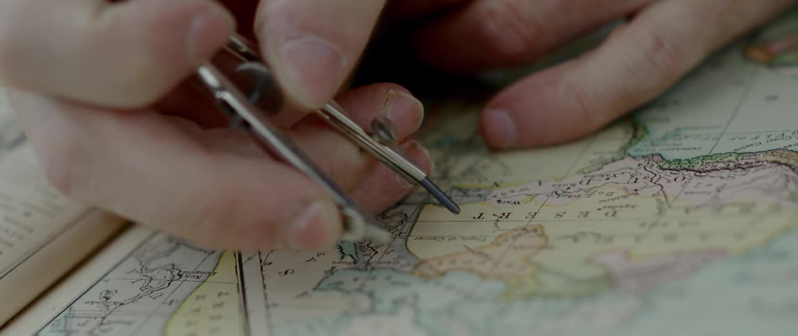 A person holds a compass as they examine a map