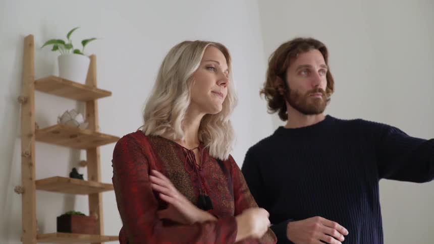 A couple contemplates inside of a new looking house while the wife is pregnant