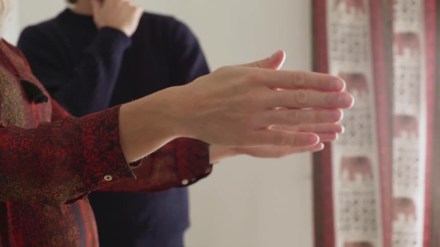 A person is showing someone the room with their hands