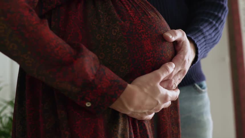 A man and pregnant woman stand together holding hands