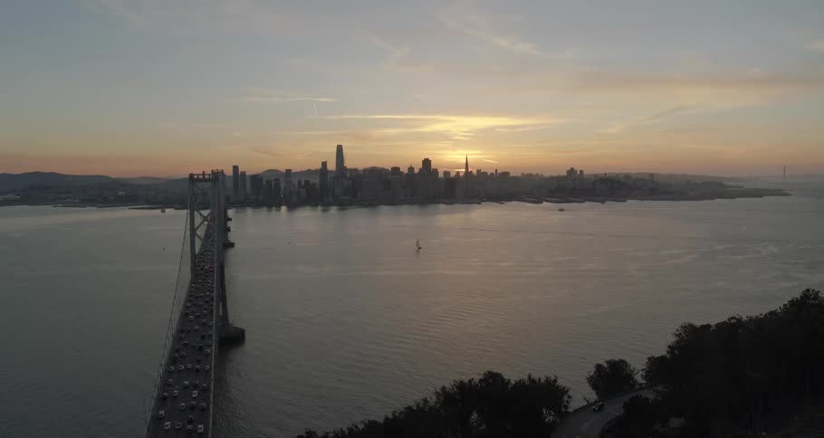 A long bridge connects a city with sloped land
