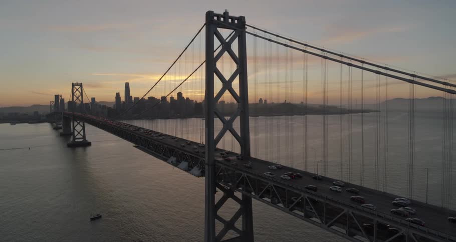 Multiple vehicles pass a long bridge to the city