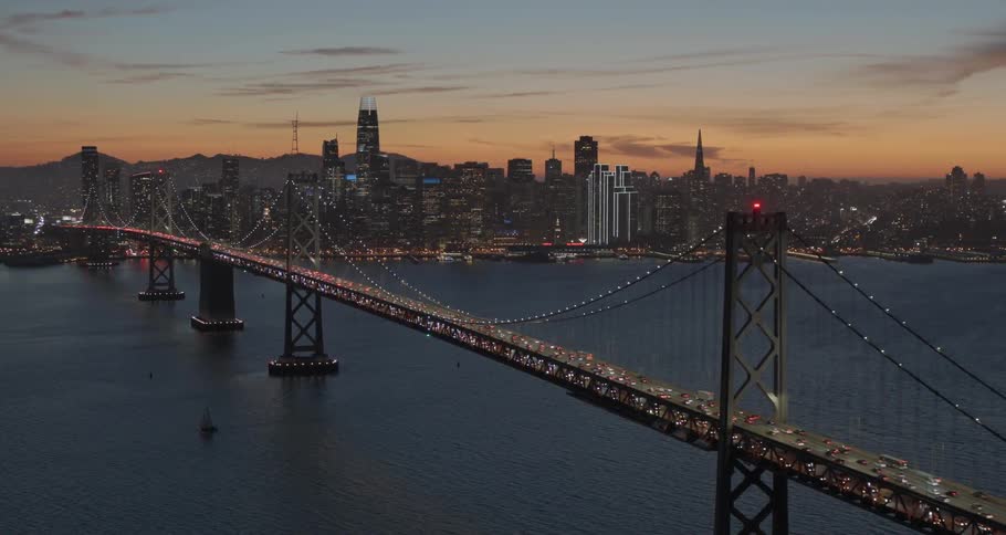 A long bridge leading to a large city at night