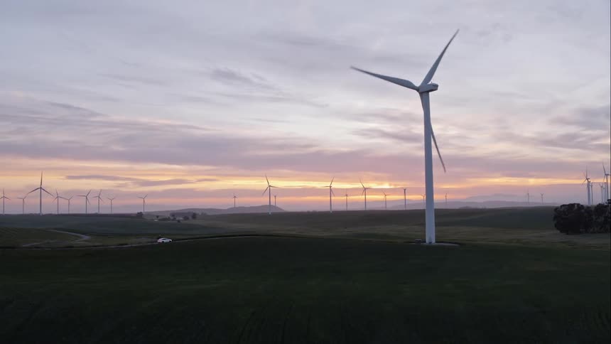 The car is driving uphill near the windmill