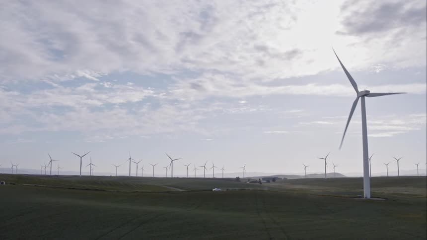 A scenery of a group of wind turbine on grass field
