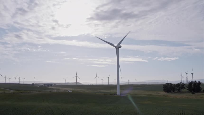 Wind turbines spinning in the wind on a vast wind farm during the day